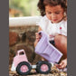 Child plays with Green Toys Pink dump truck, dumping out payload of leaves. Available at Green Distributors.