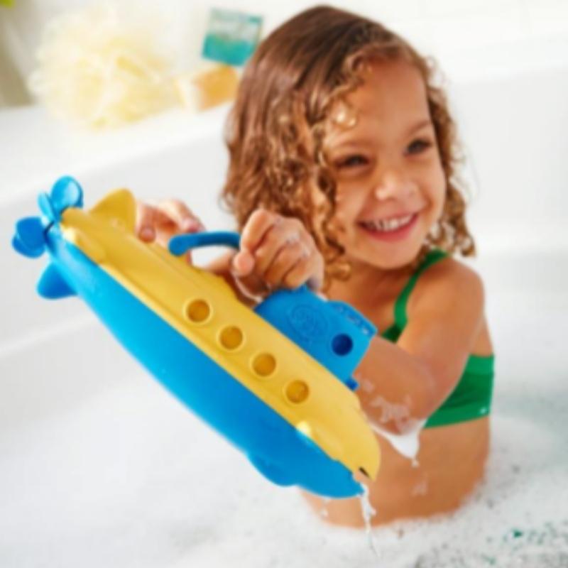 Child playing with Green Toys blue cabin handle submarine in a bubble bath. Available at Green Distributors.