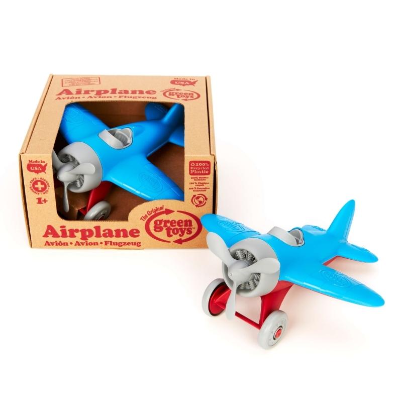 Green Toys Airplane with blue wings, red landing gear, gray propeller, cockpit, and wheels. The airplane is shown both inside and outside of cardboard box packaging. Available at Green Distributors.