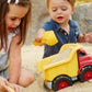 Children playing with Green Toys red dump truck in a sandbox. The kids are filling the back of the truck with sand. Available at Green Distributors.