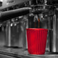 12 oz red, reusable coffee cup by Onya being filled with coffee by a barista. Available at Green Distributors.